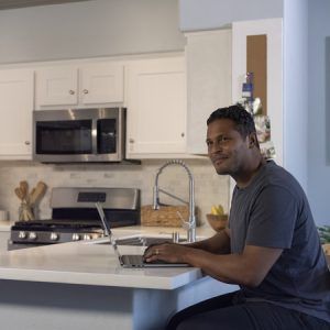 Man sitting at kitchen counter using computer