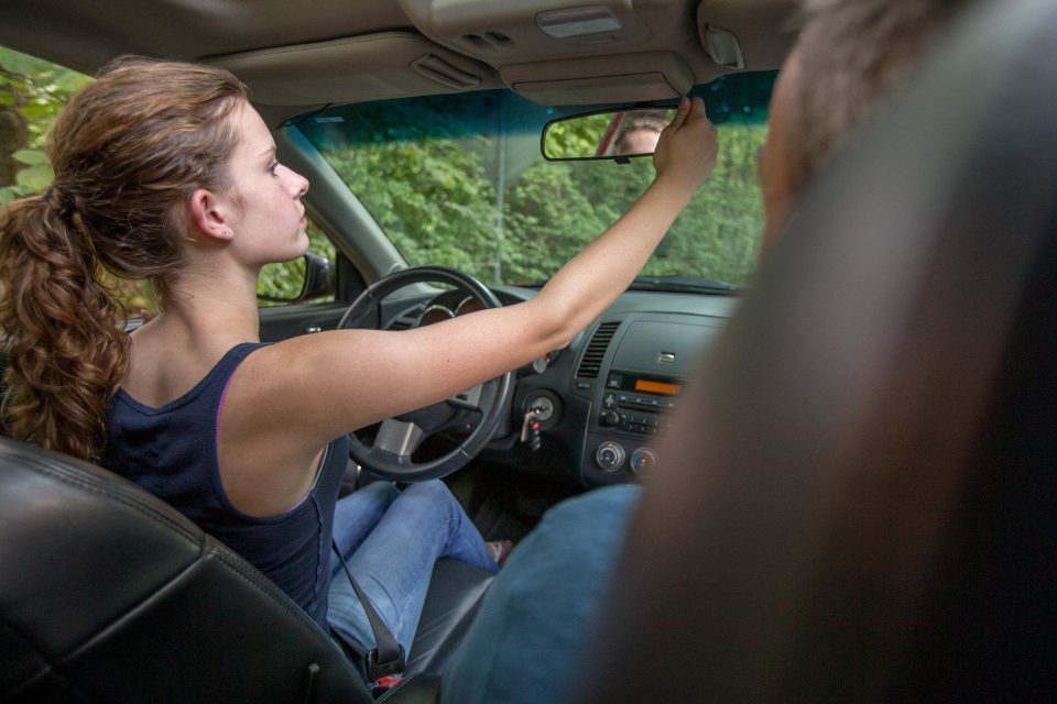 driver adjusting rear-view mirror