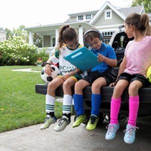 kids playing with tablet on tailgate of truck