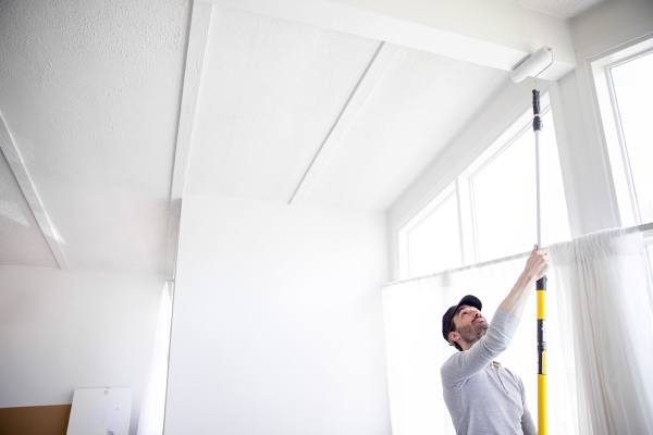 um homem pintando o teto de uma casa