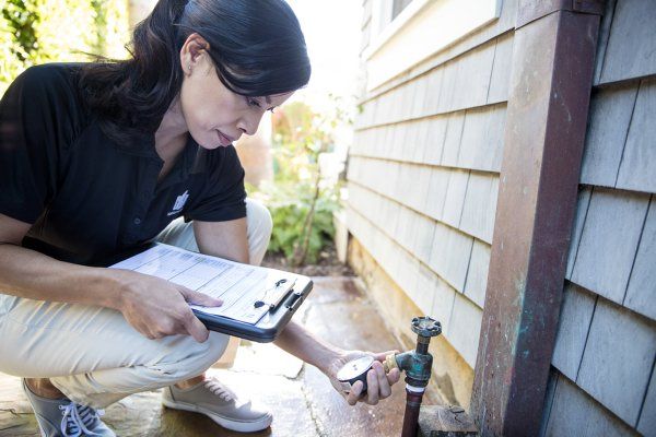 woman holding clipboard and checking water pressure from a spigot