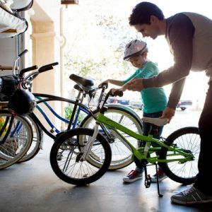 father and child putting bikes in the garage