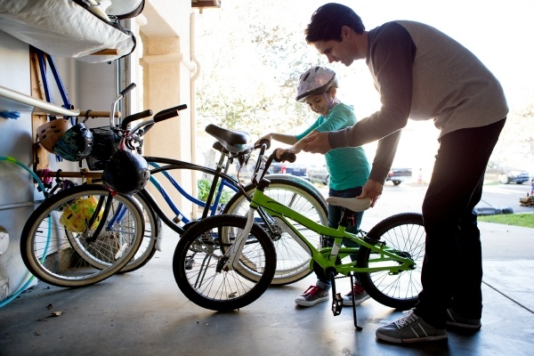 father and child putting bikes in the garage