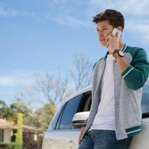 man on cell phone leaning on car