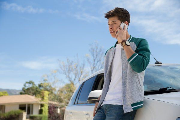 man on cell phone leaning on car