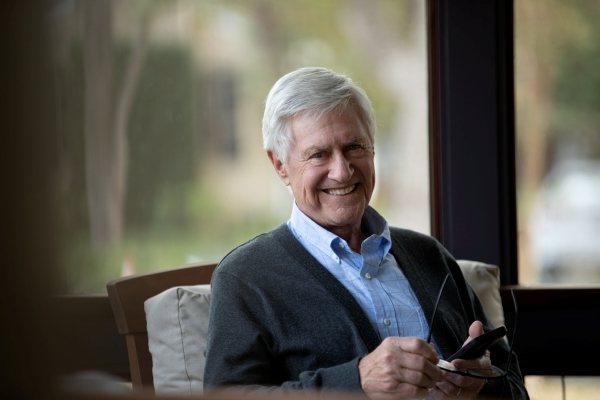 man in sweater smiling and using cell phone