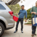 men taking bag and cooler out of car trunk