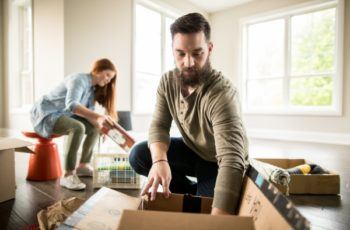 two people packing items into cardboard boxes