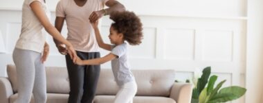 A family dances in a living room.