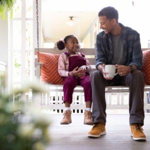 man and daughter sitting on porch swing