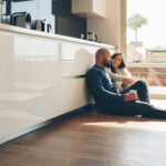 A couple sitting on the kitchen floor.