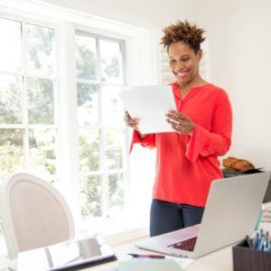 A woman reading paperwork in a home office