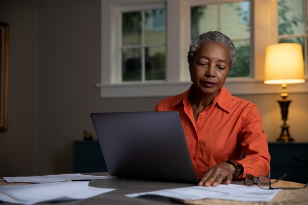 woman in orange shirt working on computer