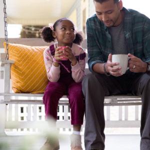 father and daughter on porch swing with coffee cups