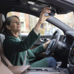 A woman checks her car’s rearview mirror.