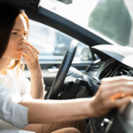 Woman in car reacting to a bad smell.