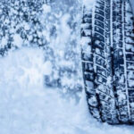 A tire covered in snow driving through a snowstorm.