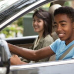 A young driver checking the side mirror while reversing the car.