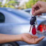 A person handing another person a set of car keys.