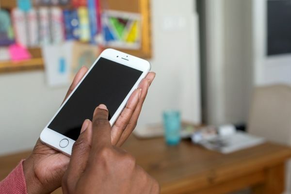 close up of hand holding an iPhone and someone touching screen