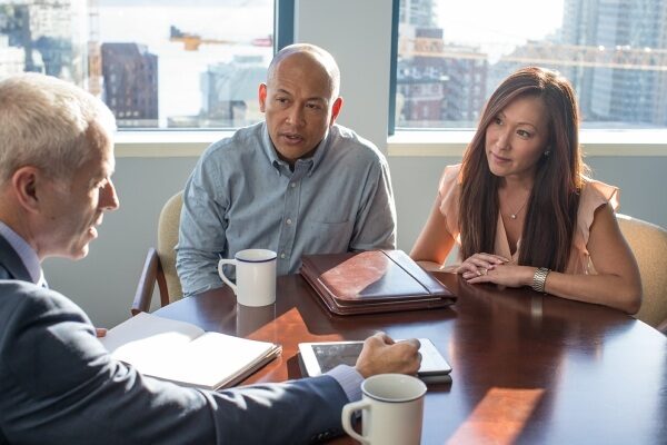 Couple discusses finances at a table with their advisor