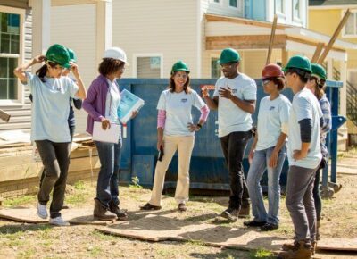 teen volunteers with hardhats in front of house