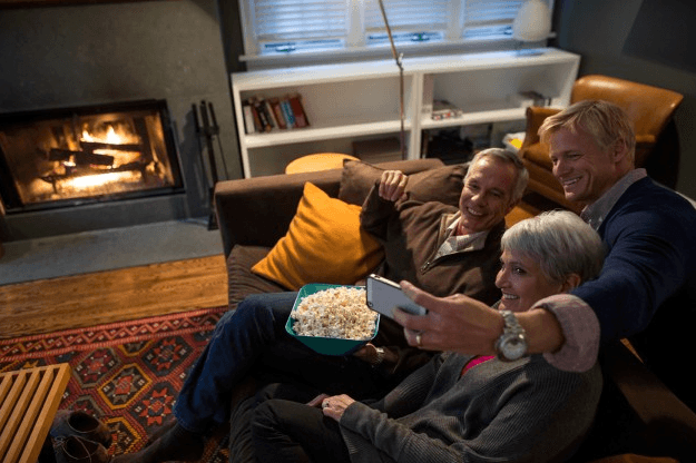 elderly couple with middle aged son taking a selfie on a sofa