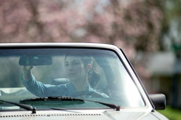 teenage girl adjusting the rear view mirror in a convertible