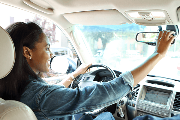 a woman checking the rear view mirror in her car