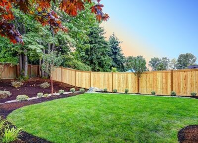 a nicely landscaped backyard with a new wooden fence