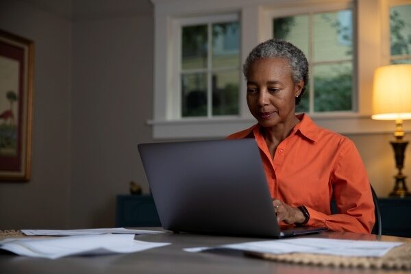 woman in orange shirt working on computer