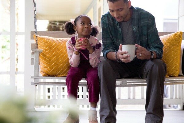 father and daughter on porch swing with coffee cups