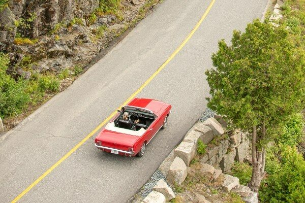 A red car driving down the road