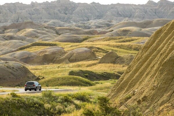 A car driving , on a road through some rocky canyons