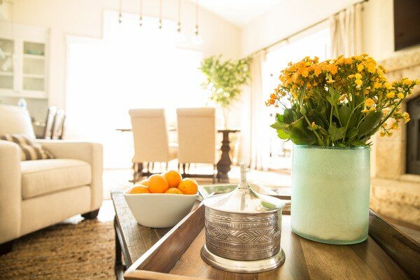 Living room table with a bowl of oranges and a vase of yellow flowers.