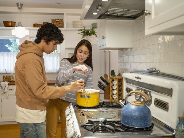 Teenage Boy and Teenage Girl Cooking at Stove