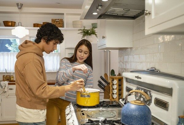 Teenage Boy and Teenage Girl Cooking at Stove