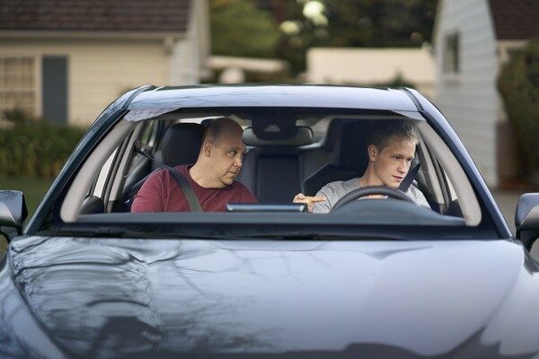 A man sitting in his car and making a concerned face.