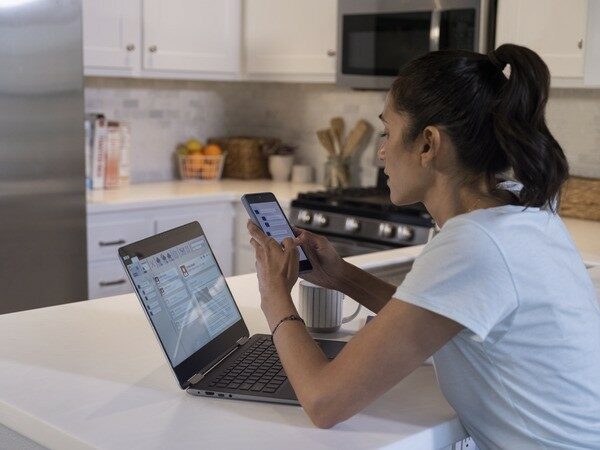 Woman at Laptop Using Cell Phone