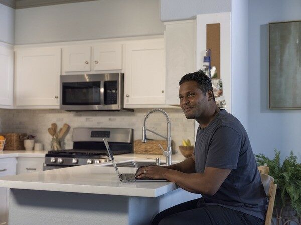 Man sitting at kitchen counter using computer
