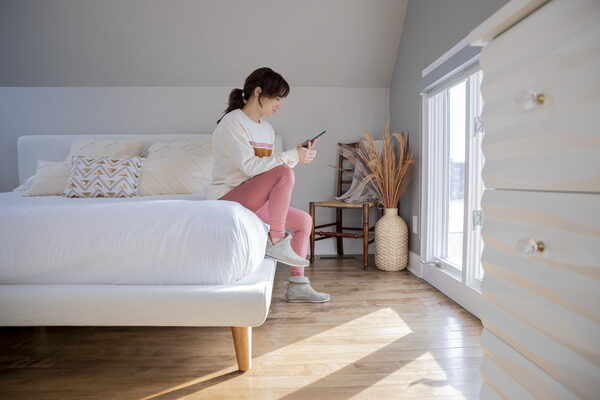 Woman looking at her phone while sitting on her bed