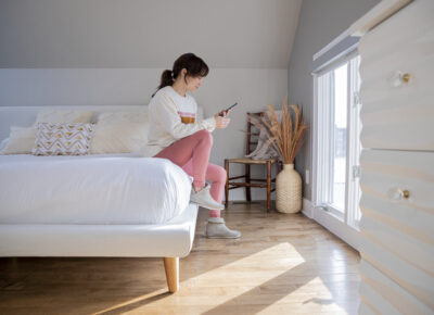 Woman looking at her phone while sitting on her bed