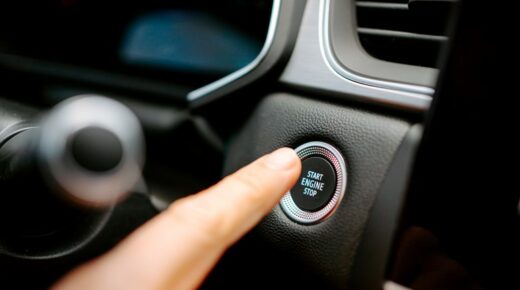 A finger pushing the start engine button in a car.