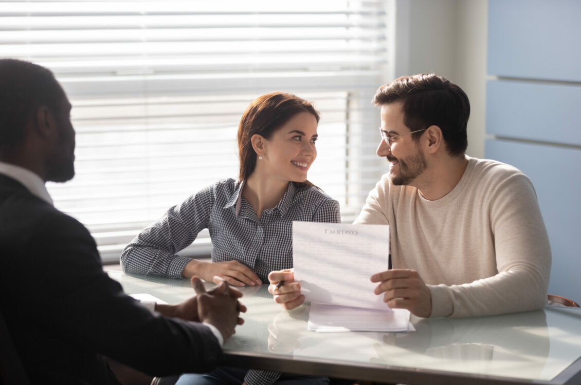 Happy family couple clients meeting african american financial consultant lawyer bank worker. Smiling married spouse buyers discussing contract details before signing, loan mortgage credit concept.