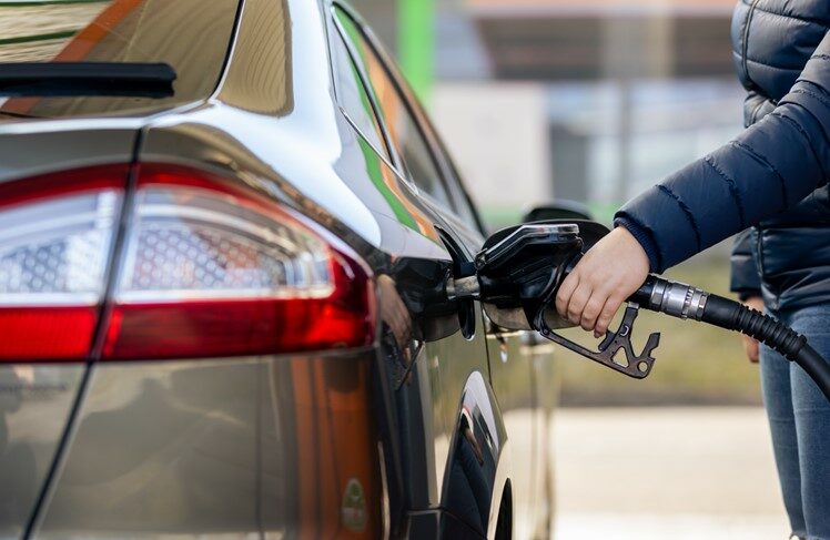 A person outdoors filling up the gas tank of a car.