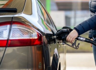 A person outdoors filling up the gas tank of a car.