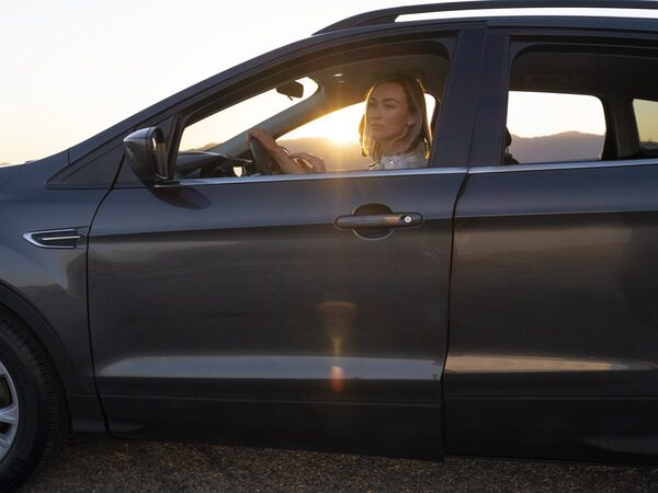 Woman driving a vehicle at sunset.