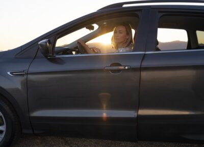 Woman driving a vehicle at sunset.