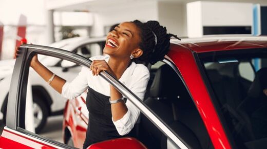 A woman smiling while leaning out of an open car door.