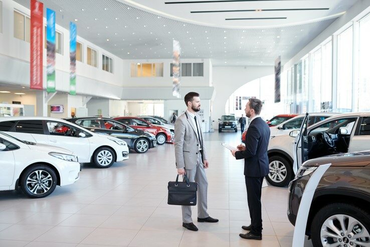 Two men standing in a car dealership.